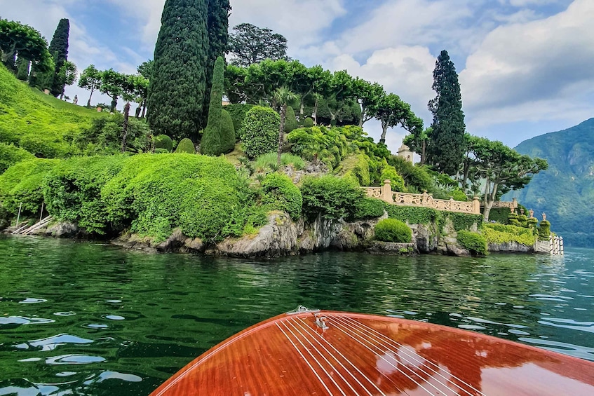 A boat on a calm lake with a lush, green hillside and tall trees in the background. 2