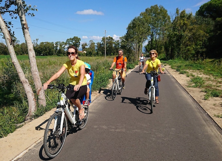 Un gruppo di persone che vanno in bicicletta su un percorso asfaltato, circondato dal verde. 1