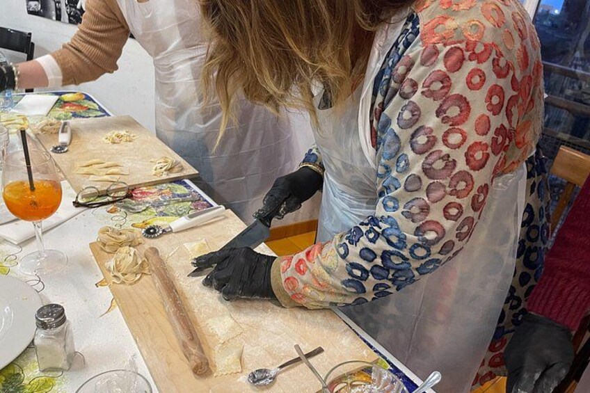 A person preparing food, possibly pasta, with a rolling pin and a cutting board. 3