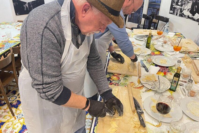 A person wearing a white apron and gloves, preparing food at a table with various dishes and utensils. 2