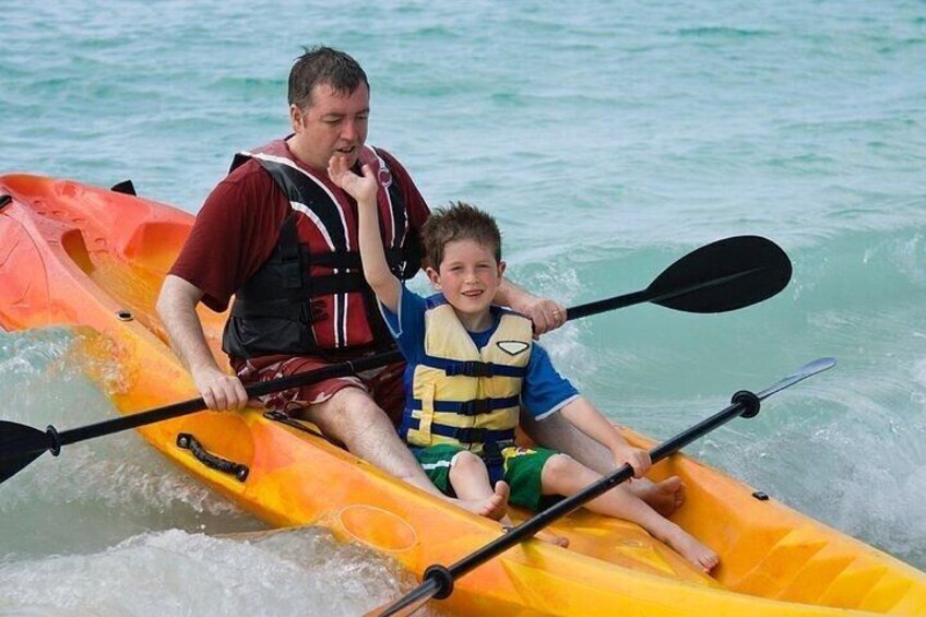 A man and a child kayaking on a turquoise sea. 2