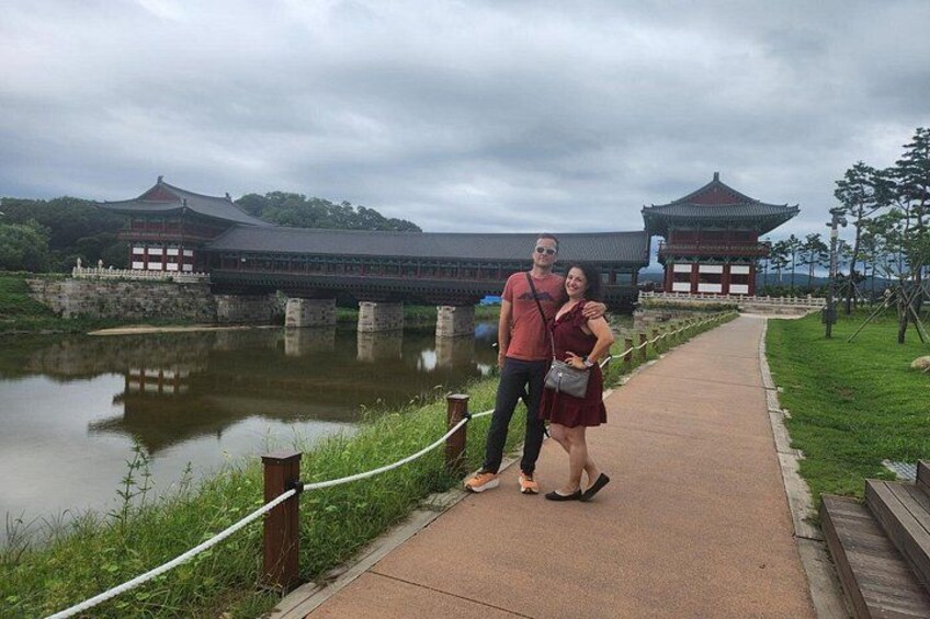 A couple standing on a pathway with traditional architecture in the background. 2