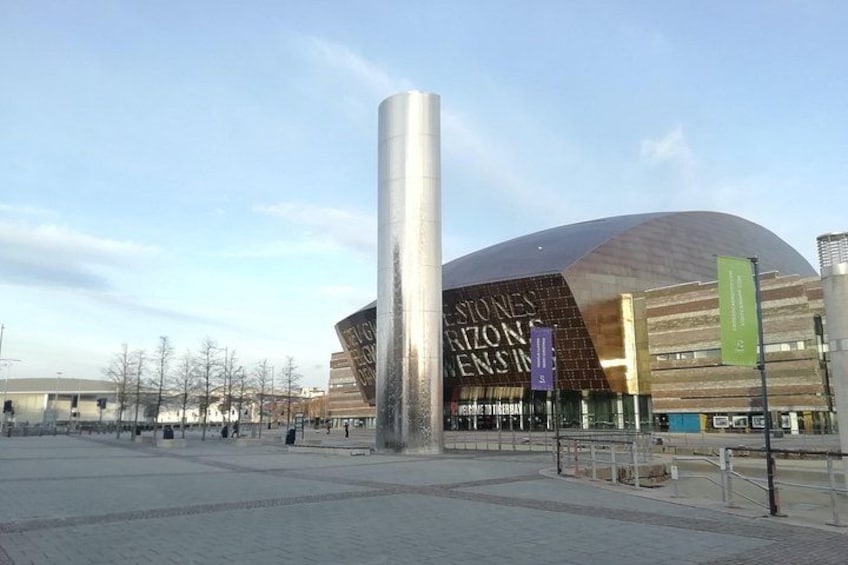 Een modern architectonisch gebouw met een gebogen dak en een hoge, cilindervormige constructie ervoor. 4
