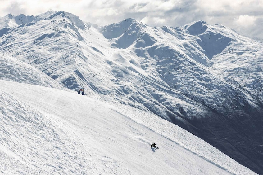 A snow-covered mountain slope with a skier descending. 5