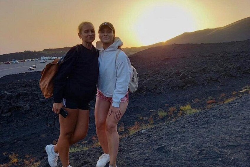 Two people standing on a rocky terrain with a sunset in the background. 4