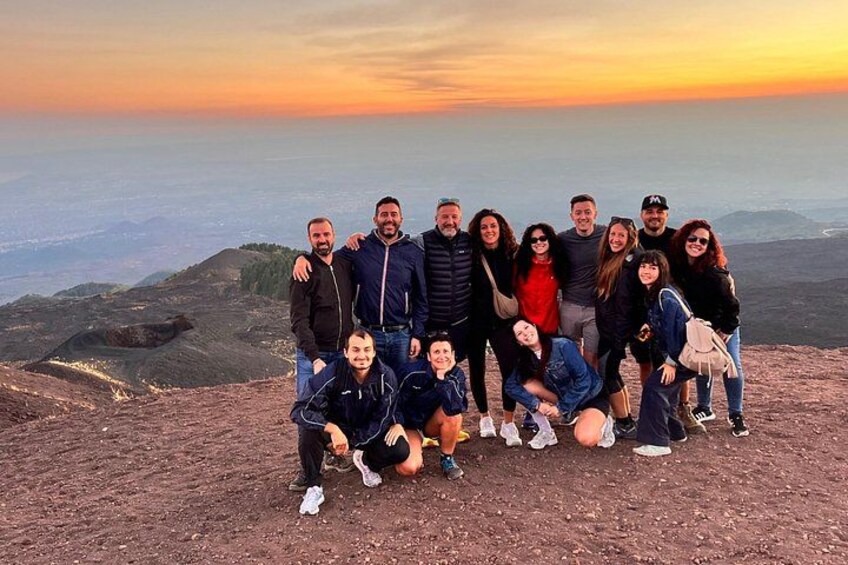 A group of people on a mountain with a sunset in the background. 4