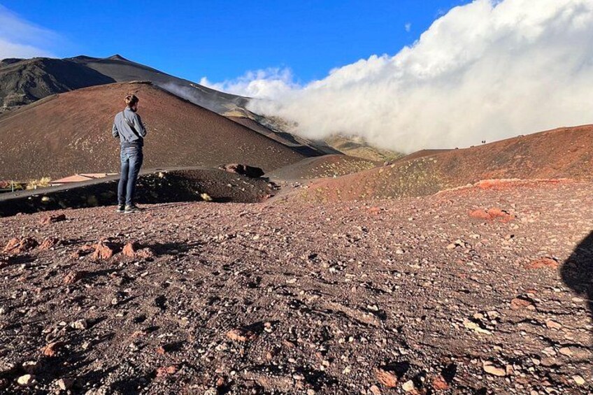 A person standing on a rocky terrain with a volcano in the background. 3