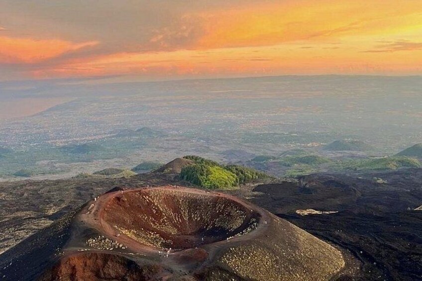 A large crater surrounded by rugged terrain and a distant cityscape. 1