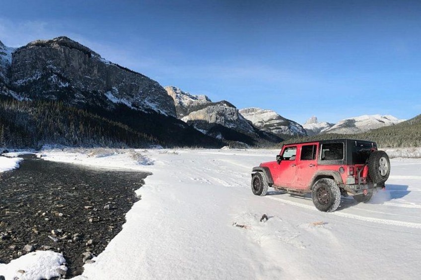 Un vehículo todoterreno rojo en un paisaje nevado con montañas al fondo. 4