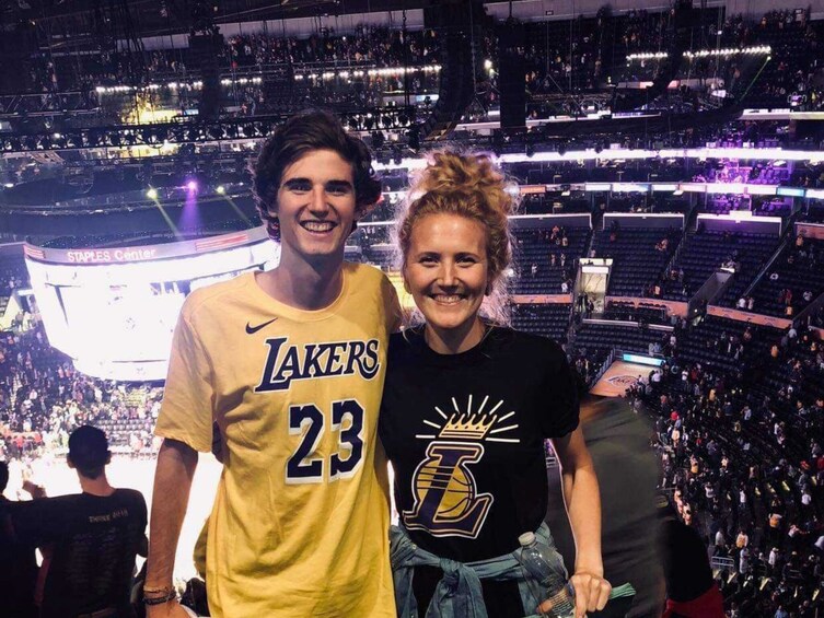 Two people standing in a stadium with a large crowd in the background. 1