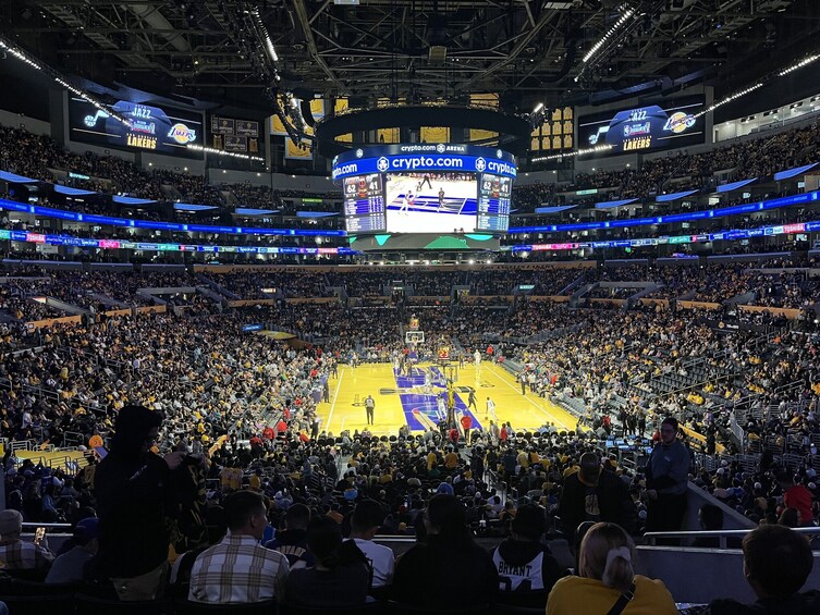 A basketball game in a large indoor stadium with a crowd of spectators. 3