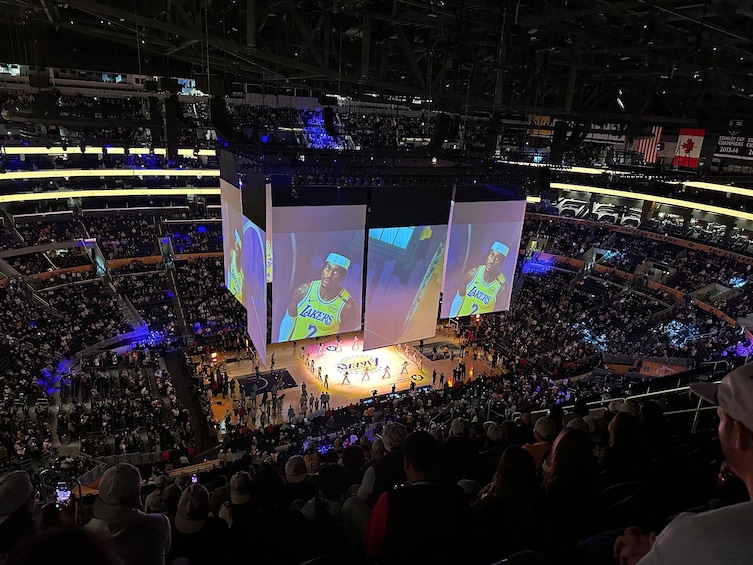 A large indoor arena with multiple screens displaying a basketball game. 2
