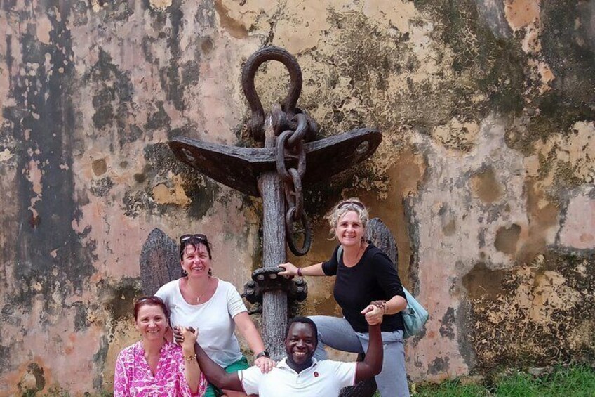 Un grupo de personas posando frente a una escultura de ancla. 1