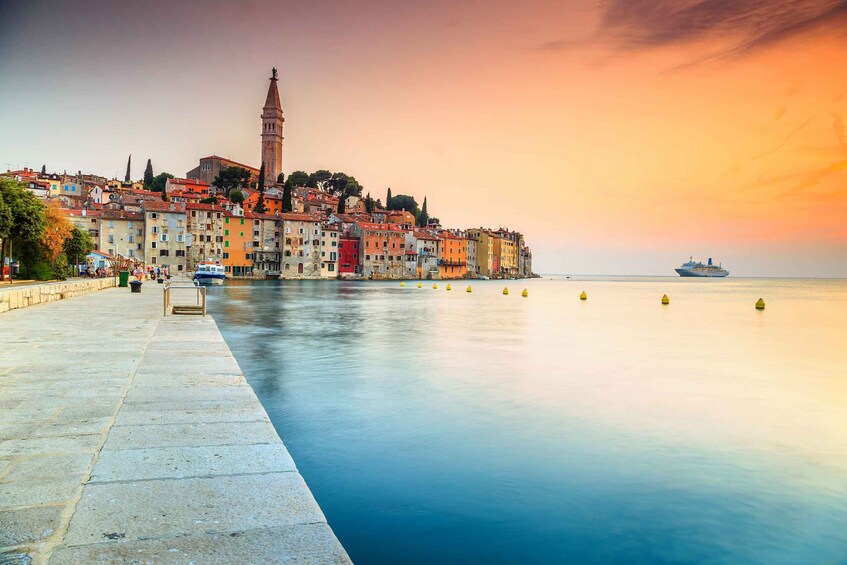 A waterfront cityscape with colorful buildings, a prominent tower, and a calm sea at sunset. 2