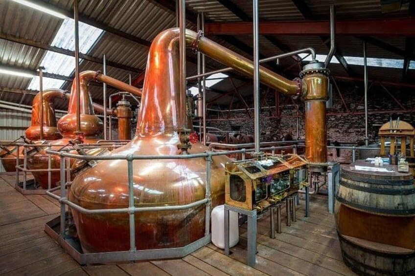 Industriële distillatieapparatuur, koperen ketels en een groot houten vat in een magazijn. 2
