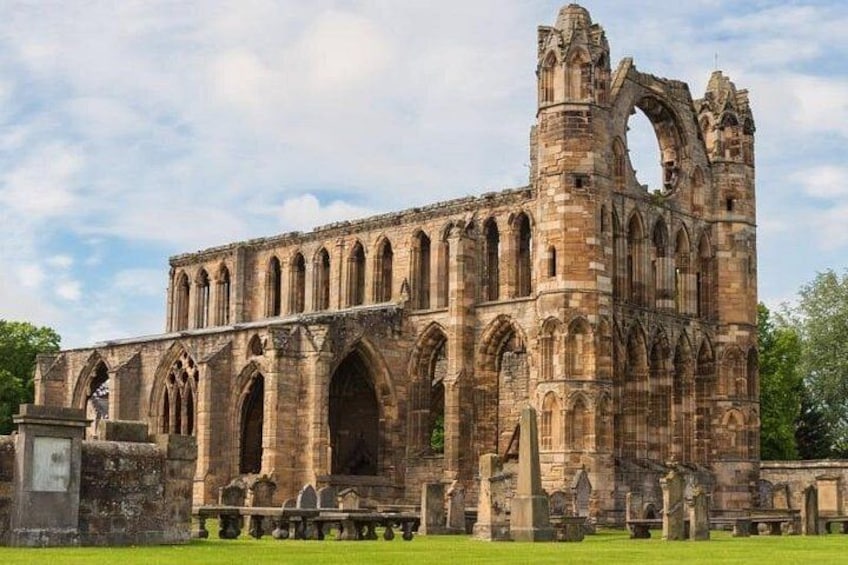 Un gran edificio de piedra histórico con múltiples arcos y una torre alta. 1
