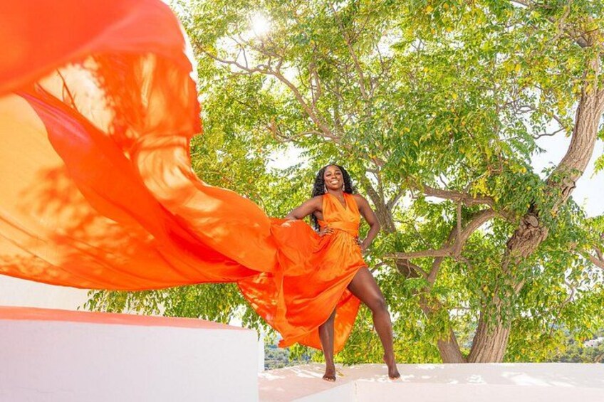 A person in an orange dress standing in front of a tree. 2