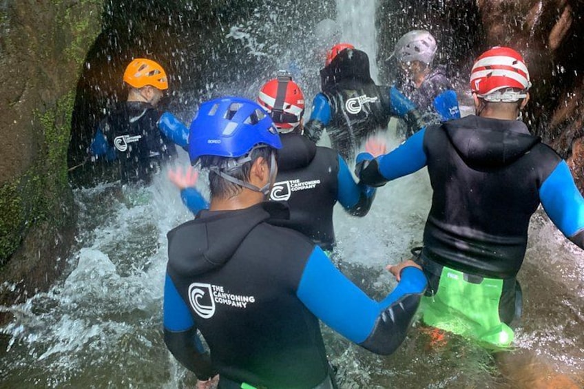 People in water with helmets and life jackets, in a rocky water setting. 3