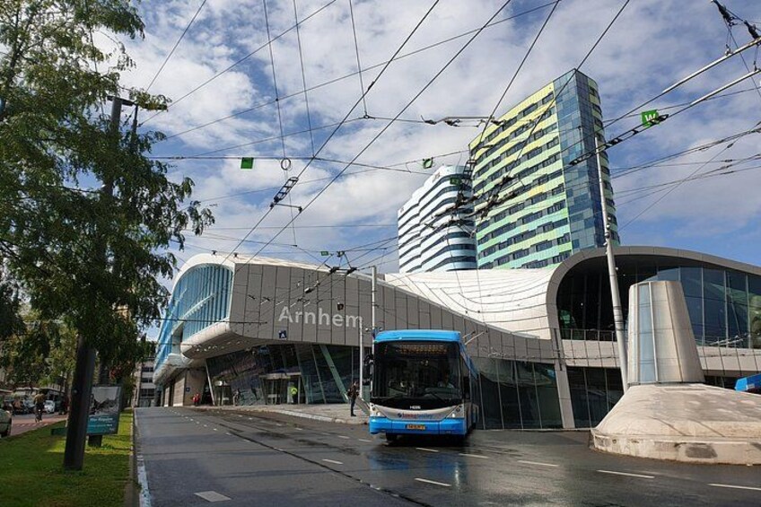 A tram on tracks, a modern building with the name 'Arnham,' and a tall skyscraper in the background. 2