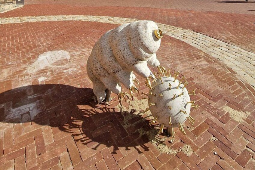 A statue of a figure in a white, textured outfit interacting with a spherical object adorned with spikes. 3