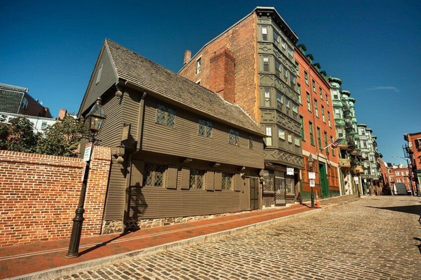 A historic building with a brick facade and a metal awning, situated on a cobblestone street. 2