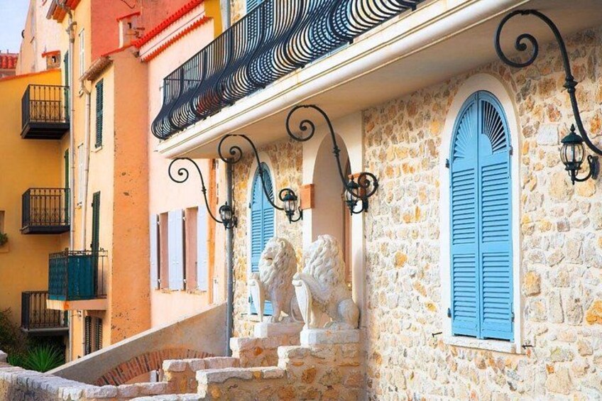 A stone building with blue shutters, a staircase, and a balcony with wrought iron railings. 4