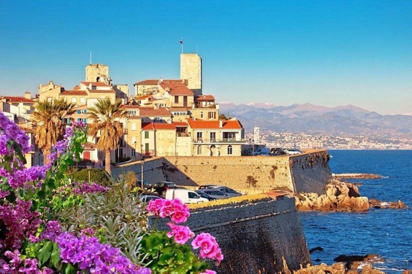 A coastal town with historic buildings, a prominent tower, and a rocky shoreline. 5
