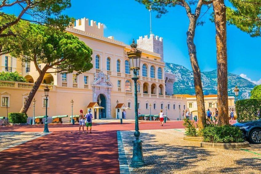 A historic building with a red-tiled courtyard, a large tree, and a mountain in the background. 3