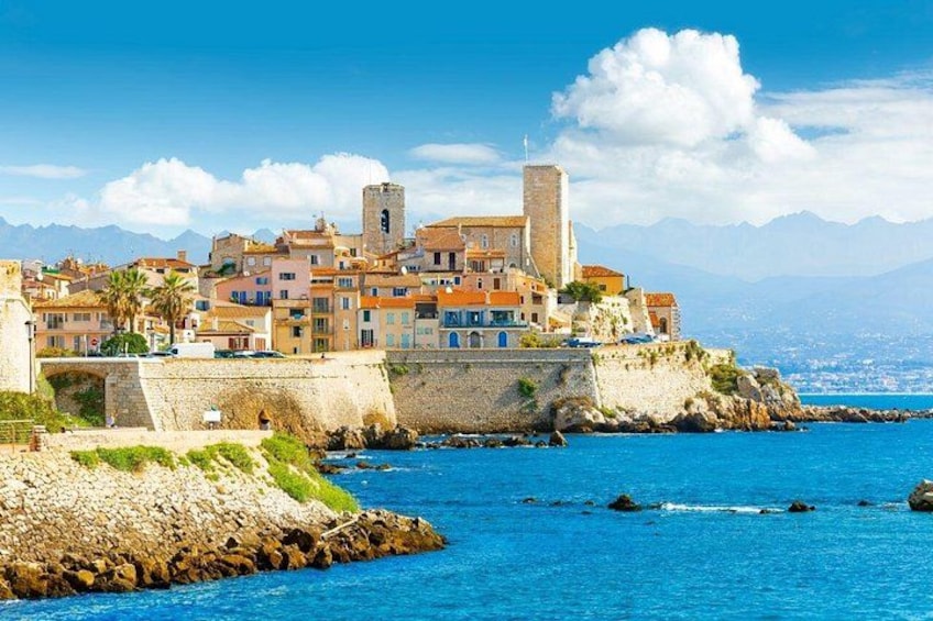 A coastal town with colorful buildings, a prominent tower, and a clear blue sea. 2