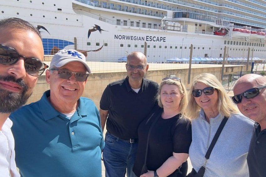 En gruppe mennesker står foran krydstogtskibet Norwegian Escape. 1