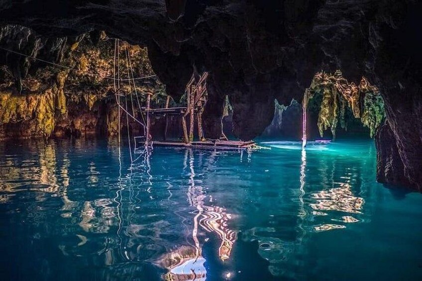 A cave with clear blue water, wooden structures, and stalactites. 2