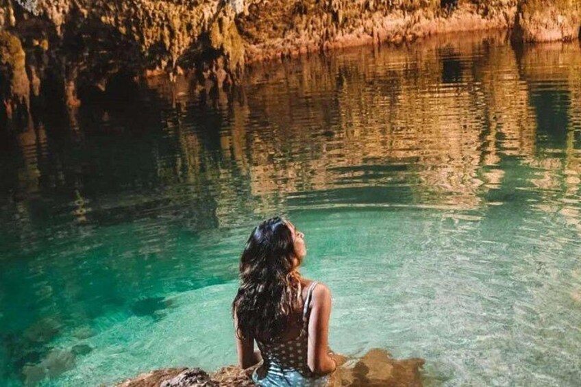 A person sitting by a clear, turquoise body of water surrounded by rocky cliffs. 5