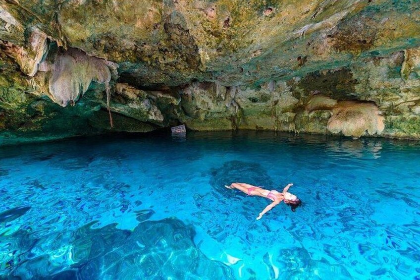 A person swimming in a clear blue pool with rocky cave walls. 3