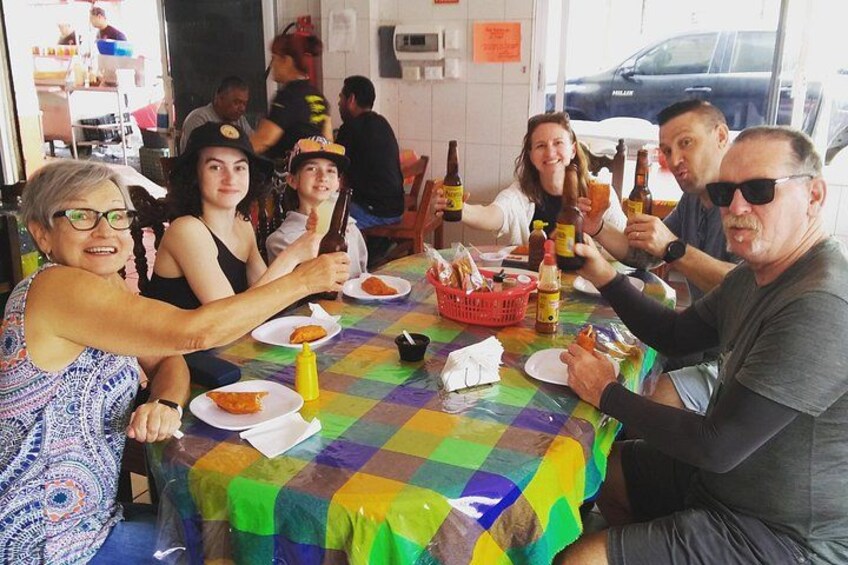Un grupo de personas sentadas alrededor de una mesa con comida y bebidas. 3