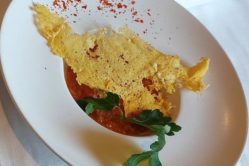 Une assiette blanche avec une crêpe pliée, une sauce rouge et une garniture. 1