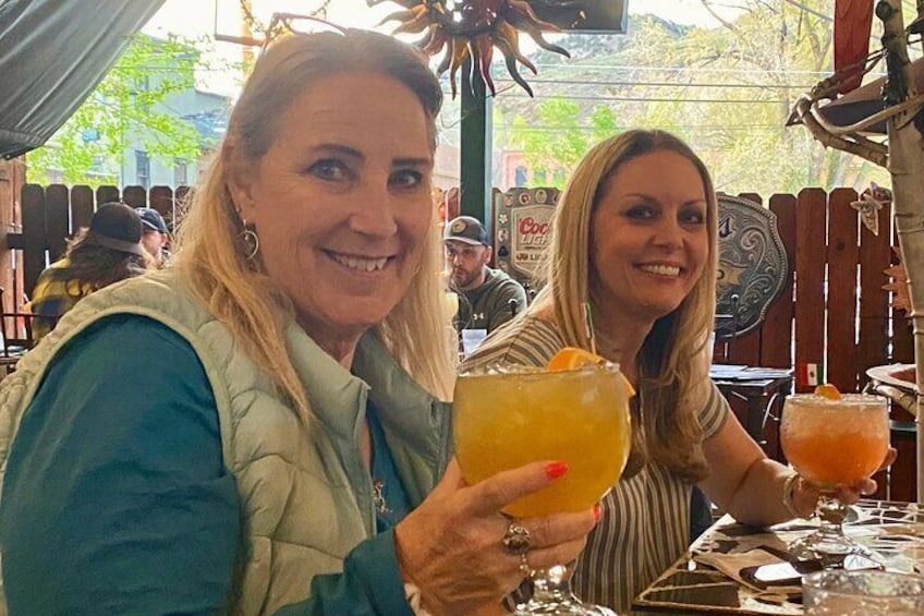 Two people sitting at an outdoor table with drinks. 1