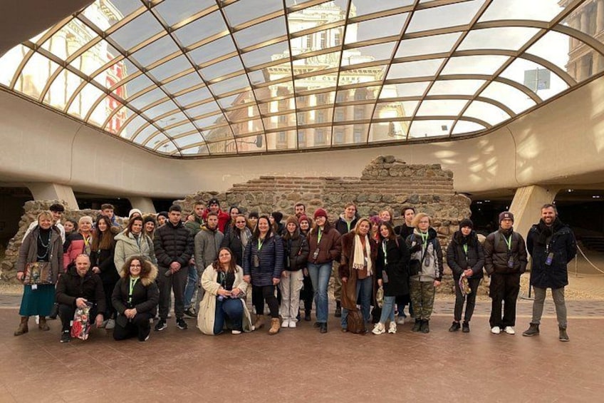 A group of people gathered in an open area with a glass ceiling structure above them. 3