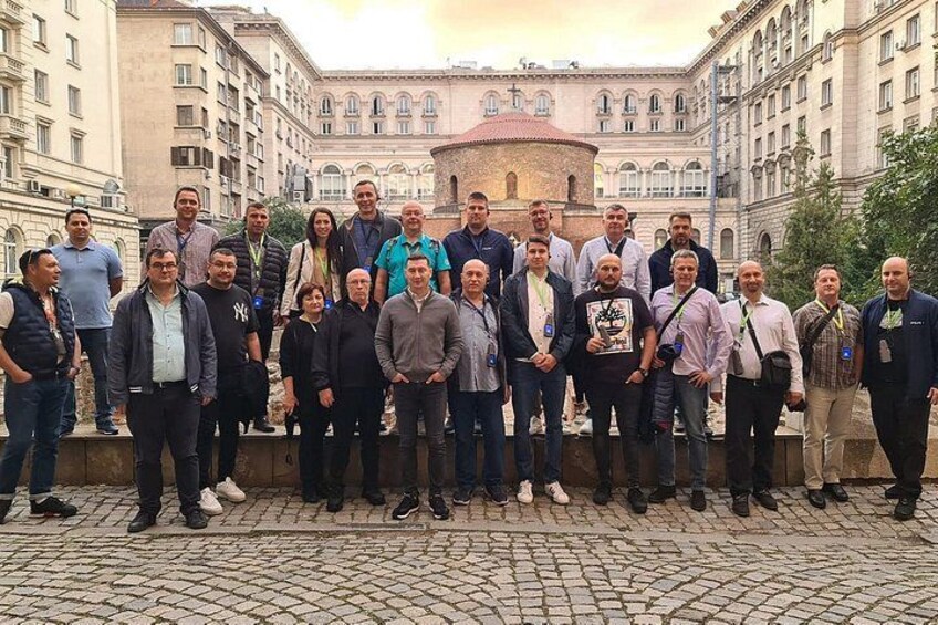 A group of people standing in front of a historic building with a dome and arched windows. 2