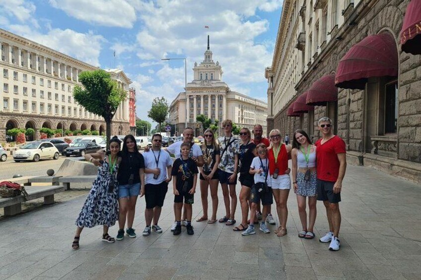 A group of people standing on a city street with historic buildings in the background. 1