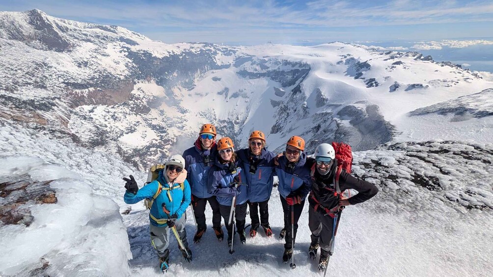 A group of skiers on a snowy mountain peak with a clear sky. 3