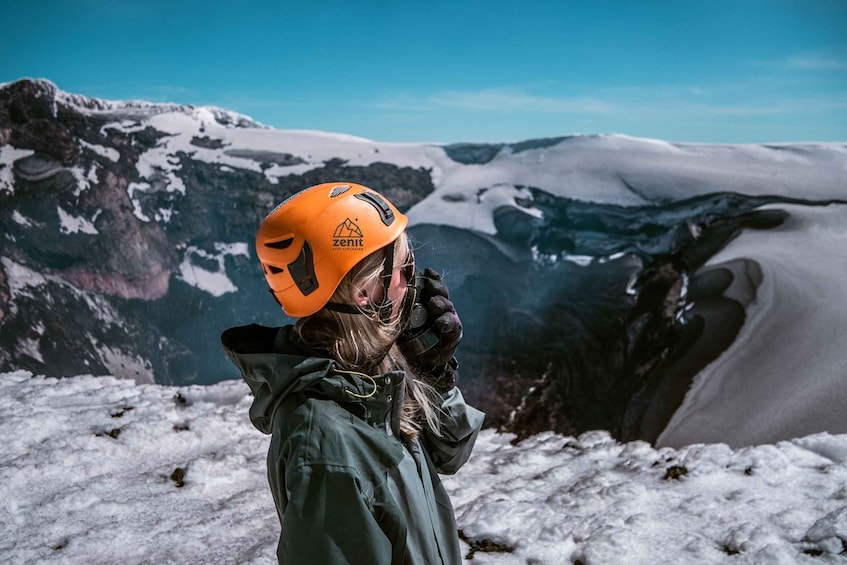 A person wearing a helmet and harness on a snowy mountain. 2