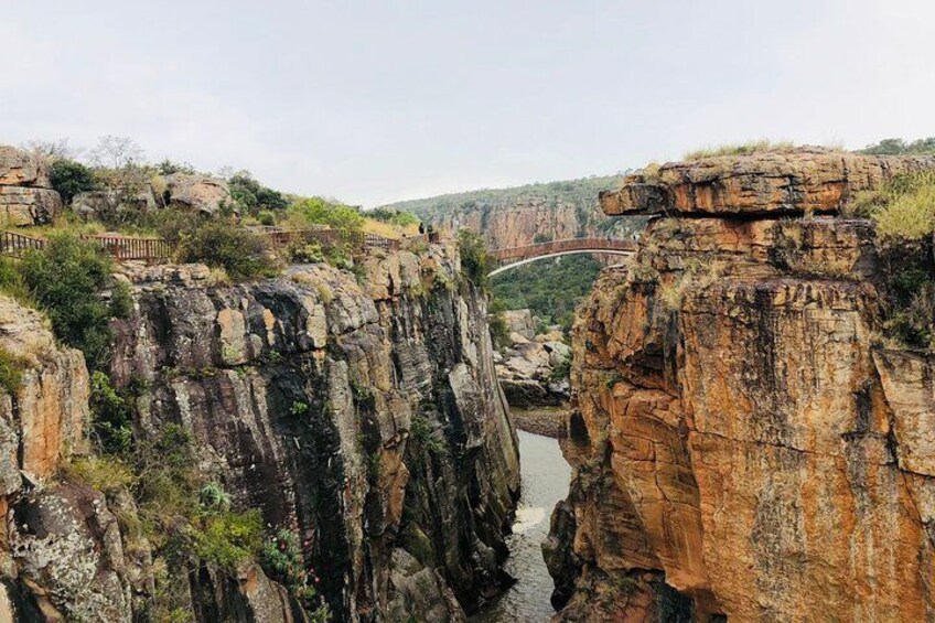 A canyon with a bridge, rocky cliffs, and a river. 4