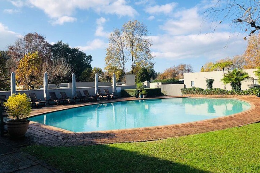 A swimming pool with lounge chairs, surrounded by a brick deck and grass. 3