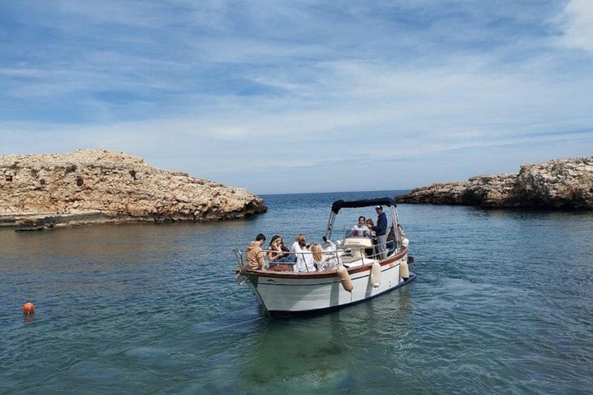 A boat with people on a calm sea, rocky shores, and clear skies. 2
