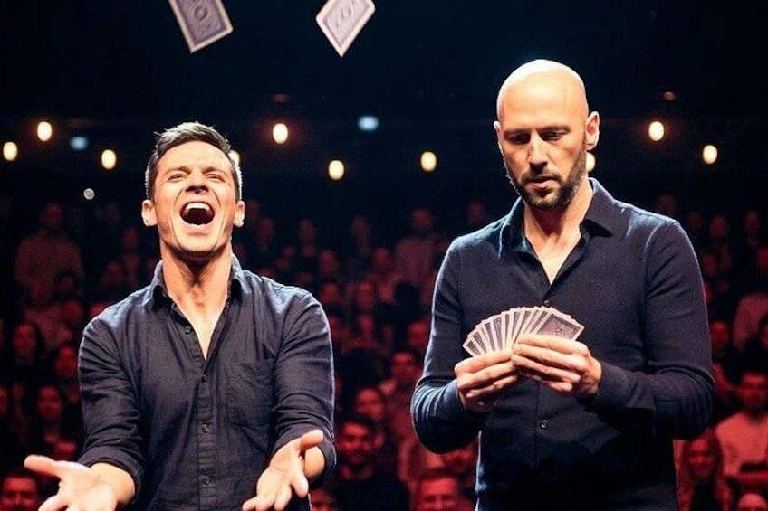 Twee mannen op het podium, met een publiek op de achtergrond. 2