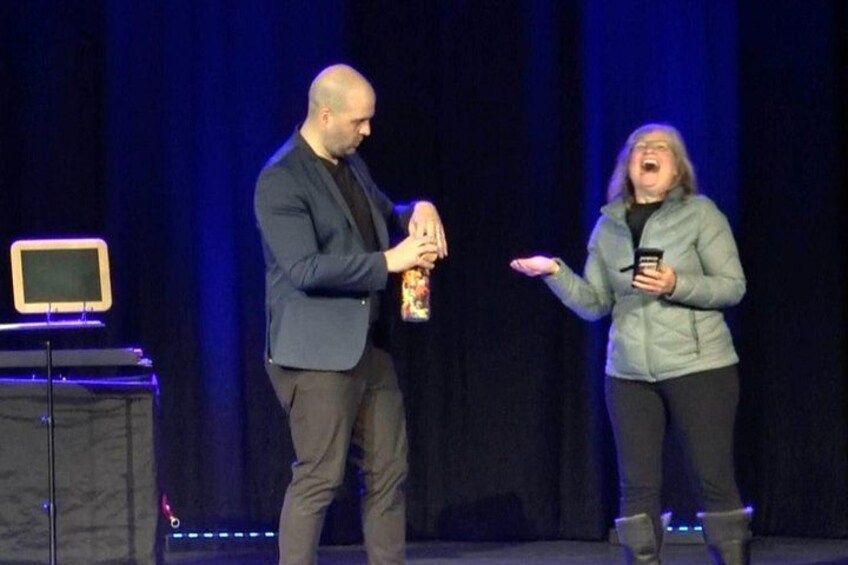 Twee personen op een podium, één met een microfoon en de ander die gebaren. 5