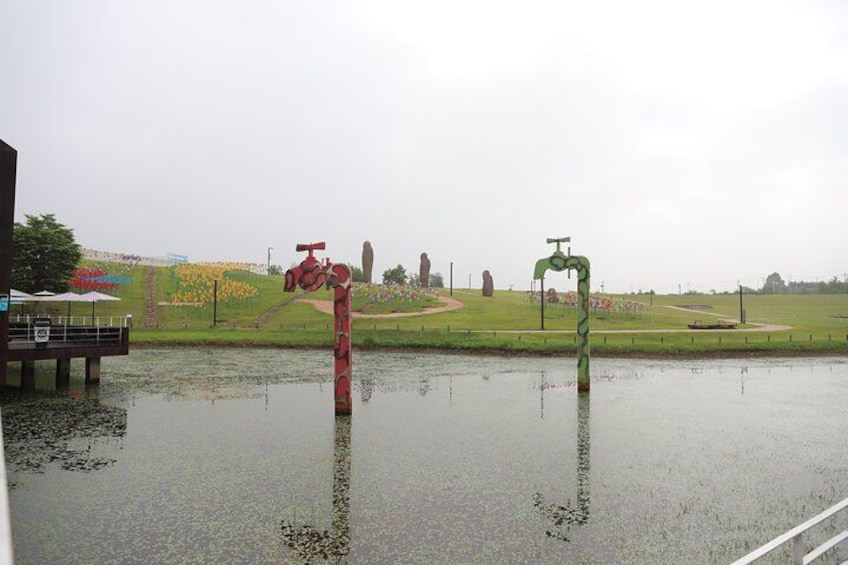 A flooded area with a red sculpture and a green sculpture in the water. 4