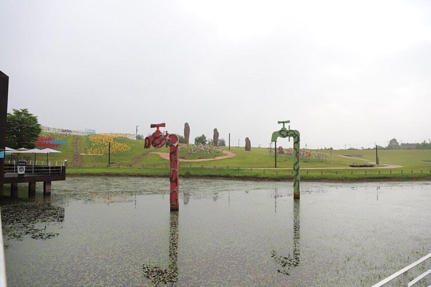 A flooded area with two large sculptures, a bridge, and distant stone formations. 4