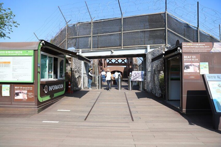 A wooden walkway leading to a building with a green information board on the left and a sign on the right. 5