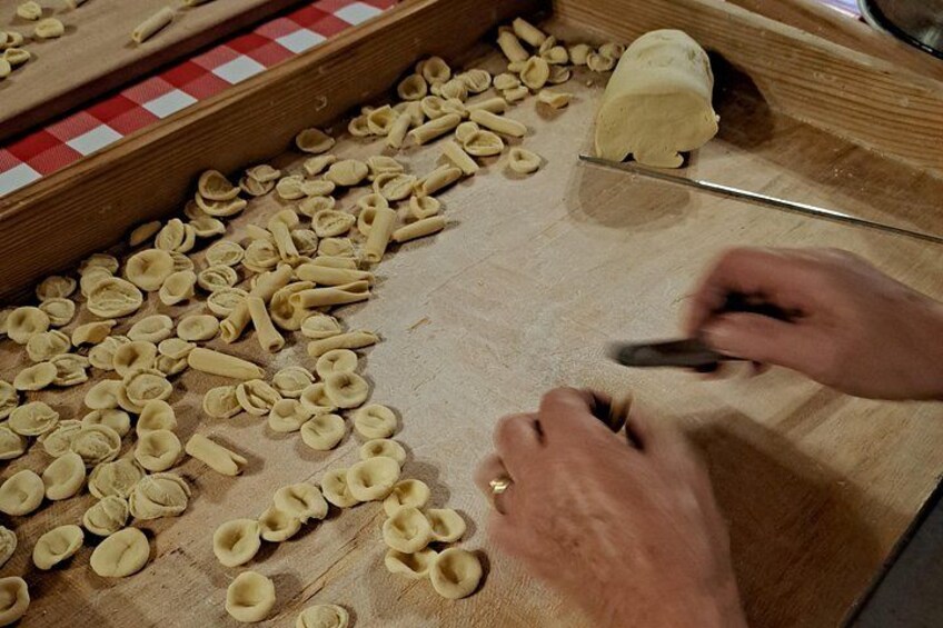 Hands shaping pasta dough on a wooden surface. 1